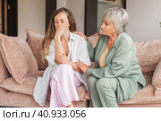 Worried aged mother embracing comforting sad grown up daughter with broken heart family sit on sofa. Стоковое фото, фотограф Гладских Татьяна / Фотобанк Лори