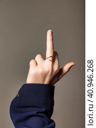 Close-up of hand of jewish teen girl showing provocative and rude gesture doing fuck you (off) symbol with middle finger. Middle finger, closeup insult on gray isolated background. Copy ad text space. Стоковое фото, фотограф Aleksandr Golubev / Фотобанк Лори