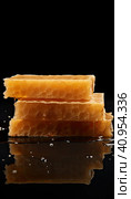 Golden wax honeycombs with honey lie on a shiny black background. Created by AI. Стоковое AI-изображение, AI-художник Ярославский Максим / Фотобанк Лори