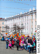 Magadan, Magadan Region, Russia - May 1, 2018. People walk down the street during a festive May Day demonstration. Men, women and children with flags and balloons. Редакционное фото, фотограф Андрей Степанов / Фотобанк Лори