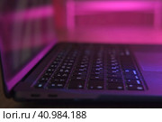 Side View of laptop computer at night. No people. Close Up keyboard, buttons. UV purple Lighting. Internet security, cyber attack. Trendy neon light. Creative vivid color of ultraviolet red and blue. Стоковое фото, фотограф Марина Демидюк / Фотобанк Лори