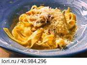 Pasta, bavette with nuts, garlic, olive oil. Side view, close-up. Pasta with parmesan cheese. Delicious spaghetti served on a blue ceramic plate. Alfredo pasta dinner, creamy white sauce. Tagliatelle. Стоковое фото, фотограф Марина Демидюк / Фотобанк Лори