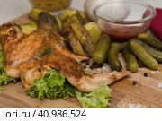 Fried chicken wings served on a wooden Board with Idaho potatoes, pickled gherkins and fresh lettuce leaves. A mug of beer is next to it. жареные куриные крылышки подаются на деревянной доске с картофелем Айдахо, маринованными корнишонами и свежими листьями салата. Рядом с ним стоит кружка пива. Стоковое фото, фотограф Дмитрий Березнев / Фотобанк Лори