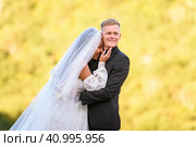Счастливые молодожены на фоне вечерней солнечной листвы, девушка смеется и уткнулась в мужа. Стоковое фото, фотограф Иванов Алексей / Фотобанк Лори