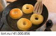 Frying process homemade and delicious donuts on fresh oil in a pan. Blue sugar topping on donuts in a home candy workshop. Pastry, sweet. Making dessert being deep fried. Preparation of donuts. Стоковое видео, видеограф Марина Демидюк / Фотобанк Лори