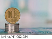 Деньги. Монета номиналом в 10 рублей на стопке монеток в 1 рубль на фоне 1000-рублевых купюр. Стоковое фото, фотограф E. O. / Фотобанк Лори