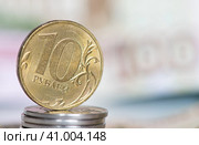 Деньги. Монета номиналом в 10 рублей на фоне 100-рублевой банкноты. Стоковое фото, фотограф E. O. / Фотобанк Лори
