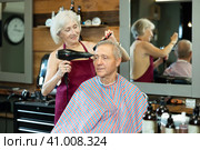 Elderly woman hairdresser dries hair with hairdryer to elderly male client. Стоковое фото, фотограф Яков Филимонов / Фотобанк Лори