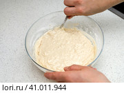 Woman's hands with an yeast dough. The woman is stirring the baking dough in a glass bowl. Женские руки с дрожжевым тестом. Женщина замешивает тесто для выпечки в стеклянной миске. Стоковое фото, фотограф Дмитрий Березнев / Фотобанк Лори