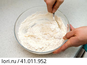 Woman's hands with an yeast dough. The woman is stirring the baking dough in a glass bowl. Женские руки с дрожжевым тестом. Женщина замешивает тесто для выпечки в стеклянной миске. Стоковое фото, фотограф Дмитрий Березнев / Фотобанк Лори