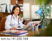 Young Hispanic female doctor working with laptop in office. Стоковое фото, фотограф Яков Филимонов / Фотобанк Лори