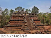 Angkor. Cambodia. Ruins of the Phimeanakas temple. Red building in the form of a stepped pyramid, with a staircase. Upstairs, a dilapidated terrace, a colonnade. Background - blue sky, jungle. (2019 год). Стоковое фото, фотограф Вера Ивановна Кубарева / Фотобанк Лори