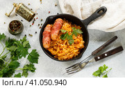 Stewed cabbage with carrots, onions and tomatoes and sausages in bacon with parsley and spices in a cast iron pan. Bigos. Delicious lunch. Стоковое фото, фотограф Виктория Панченко / Фотобанк Лори