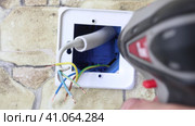 An electrician tightens screw while installing temperature control device into wall socket. Стоковое видео, видеограф Владимир Григорьев / Фотобанк Лори
