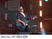 Музыкант, лидер рок-группы "7Б" Иван Демьян в, во время выступления на сцене стадиона спортивнго комплекса Лужники в День флага России, в городе Москве, Россия (2023 год). Редакционное фото, фотограф Николай Винокуров / Фотобанк Лори