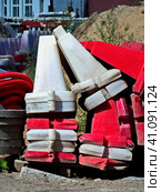 Plastic divider road blocks in white and red are stacked on top of each other. Building materials are stacked nearby. Стоковое фото, фотограф Бузмакова Светлана / Фотобанк Лори