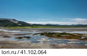 Streams from hot springs are visible in the caldera of an extinct volcano. Sulphurous deposits on sandy soil. A picturesque mountain range against a blue sky. Kamchatka. Uzon. Стоковое фото, фотограф Вера Ивановна Кубарева / Фотобанк Лори