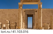 The courtyard of the Karnak Temple. There are drawings and hieroglyphs on the stone wall. Fragments of columns. In the open doorway - the blue sky, the expanse, the city in the distance. Egypt. Luxor (2021 год). Стоковое фото, фотограф Вера Ивановна Кубарева / Фотобанк Лори