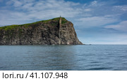 Picturesque rocky cape of Kamchatka in the Pacific Ocean. Steep slopes against a background of blue sky and clouds. Avacha Bay. Стоковое фото, фотограф Вера Ивановна Кубарева / Фотобанк Лори