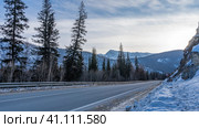 The asphalt road goes into the distance along the mountain slope. A road sign on the snowy side of the road. Coniferous trees and a mountain range against the sky. Altai. Chuysky tract. Стоковое фото, фотограф Вера Ивановна Кубарева / Фотобанк Лори