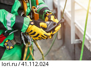 Close up of man hands industrial mountaineer worker in work uniform with rope equipment on roof building. Access climber high-rise rope dangerous job. Industry urban works concept. Copy ad text space. Стоковое фото, фотограф Aleksandr Golubev / Фотобанк Лори