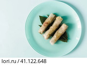 Спринг-роллы с начинкой из морепродуктов и овощей декорированных зеленым листом на светлом фоне, место для текста. Стоковое фото, фотограф Лозовая Людмила / Фотобанк Лори