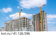 A tower construction crane on the background of a blue sky with clouds. The frame of a building under construction. Building construction. Load-bearing reinforced concrete walls of the house. Стоковое фото, фотограф Эдуард Белкин / Фотобанк Лори