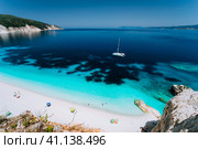 Azure water of Fteri beach, Cephalonia Kefalonia, Greece. White catamaran yacht in clear blue sea water. Tourists on sandy beach near azure lagoon (2018 год). Стоковое фото, фотограф Igor Tichonow / Фотобанк Лори