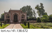 The ancient building in the Itmad-Ud-Daula tomb complex is made of red sandstone decorated with white ornaments. Arches, domes, latticed windows are visible. Green vegetation. India. Agra (2022 год). Стоковое фото, фотограф Вера Ивановна Кубарева / Фотобанк Лори