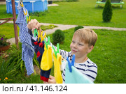 A happy caucasian 9 years boy helps her mother to hang up clothes. Development of fine motor skills through household activities. Selective focus. Стоковое фото, фотограф Ирина Старикова / Фотобанк Лори