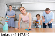 Teenage daughter dusting the table while parents and youngest daughter clean up room. Стоковое фото, фотограф Яков Филимонов / Фотобанк Лори