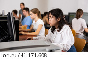 Portrait of fifteen-year-old schoolgirl studying at computer in class at an informatics lesson with classmates. Стоковое фото, фотограф Яков Филимонов / Фотобанк Лори