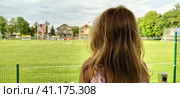 Sremska Mitrovica, Serbia, August 1, 2020. A girl sits with her back to the camera and watches a football match of childrens teams. Beautiful long blonde hair. Soccer fans in a match. Редакционное фото, фотограф Юлия Петровская / Фотобанк Лори