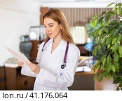Doctor woman standing in hall with sheets of paper in hands. Стоковое фото, фотограф Яков Филимонов / Фотобанк Лори