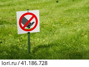 Photo of warning sign, which is meaning that walking on grass is strictly prohibited. The sign is installed in the park on the edge of the lawn area. Фотография предупреждающего знака, который означает, что ходить по траве строго запрещено. Знак установлен в парке на краю газонной зоны. Стоковое фото, фотограф Дмитрий Березнев / Фотобанк Лори