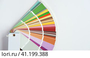 Female Hand opening Color guide close up. Assortment of Colour samples for design. Colors palette fan on white concrete wall background. Graphic designer chooses colors. Coloured swatches catalogue 4K. Стоковое видео, видеограф Марина Демидюк / Фотобанк Лори