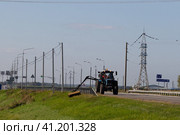 Трактор скашивает траву на обочине. Трасса М3 (2023 год). Редакционное фото, фотограф Дмитрий Неумоин / Фотобанк Лори