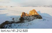 Shamanka Rock or Cape Burkhan in winter. Frozen Lake Baikal in the snow. Aerial view. Скала Шаманка или мыс Бурхан зимой. Замерзшее озеро Байкал в снегу. Стоковое видео, видеограф Виктория Тельминова / Фотобанк Лори