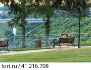 July 23, 2022 Russia Tver region Rzhev city. People sit on a bench on the embankment of the Volga River. Редакционное фото, фотограф Алексей Сорокин / Фотобанк Лори