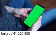 The green screen of a smartphone or chroma key. Women's hands hold the phone, click the touch screen. Close up Mock up. Стоковое видео, видеограф Глущенко Елена / Фотобанк Лори