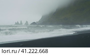 The black sand beach of Reynisfjara with waves hitting the shore on foggy rainy stormy day Vik, Icel. Стоковое видео, видеограф Igor Tichonow / Фотобанк Лори