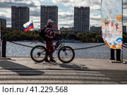 Мужчина стоит с велосипедом на набережной Северного Речного вокзала в солнечный день во время проведения Московского осеннего велофестиваля в городе Москве, Россия (2023 год). Редакционное фото, фотограф Николай Винокуров / Фотобанк Лори
