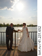 Sremska Mitrovica, Serbia October 10, 2019: the bride and groom hold hands and look forward. The river and the sun are visible in the background. Стоковое фото, фотограф Юлия Петровская / Фотобанк Лори