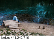 A girl is sitting on the shore of a blue lake. Beautiful natural background. Blue Lake in Kazan. Russia, Republic of Tatarstan, Kazan, September 2023. Стоковое фото, фотограф Photojuli / Фотобанк Лори
