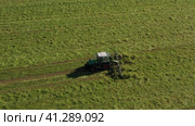 Harvesting and drying hay. The grass tedder turns freshly cut grass. Drone photo. Стоковое видео, видеограф Артем Лукин / Фотобанк Лори