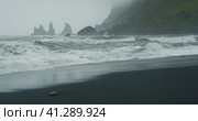 The black sand beach of Reynisfjara with waves hitting the shore on foggy rainy stormy day Vik, Icel. Стоковое фото, фотограф Igor Tichonow / Фотобанк Лори