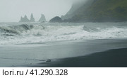 The black sand beach of Reynisfjara with waves hitting the shore on foggy rainy stormy day Vik, Icel. Стоковое фото, фотограф Igor Tichonow / Фотобанк Лори