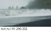 The black sand beach of Reynisfjara with waves hitting the shore on foggy rainy stormy day Vik, Icel. Стоковое видео, видеограф Igor Tichonow / Фотобанк Лори