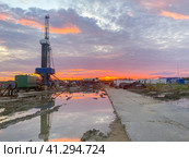 An oil field with an oil rig and wagons. Reflection in a puddle at sunset. Oil industry. Стоковое фото, фотограф Коханова Наталья / Фотобанк Лори