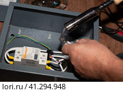 Soldering the elements of the electrical circuit of the modular contactor of the heating system of the cottage. Anapa, Russia-04.09.2021. Редакционное фото, фотограф Коханова Наталья / Фотобанк Лори